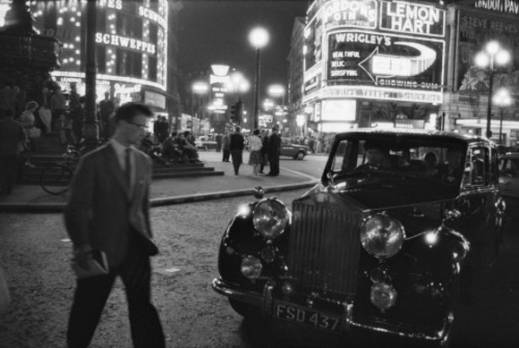 A man cuts across traffic at Piccadilly Circus; 1960